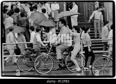 Chine Shanghai quelques jours après le massacre de la place Tiananmen en juin 1989. Les numérisations effectuées en 2018, hommes et femmes sur les bicyclettes à Shanghai sous la pluie. Banque D'Images