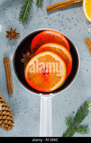 Vue de dessus sur un pot avec boisson traditionnelle de Noël vin chaud avec des tranches d'orange, l'anis et des bâtons de cannelle parmi les décorations d'hiver. Banque D'Images