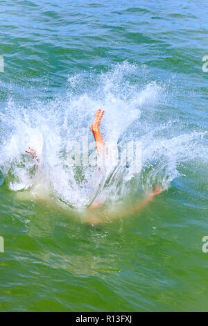 Jeune homme, adolescent, désactivation, sauter dans la mer au large de Broadstairs port. Grand plouf est il touche l'eau. Banque D'Images