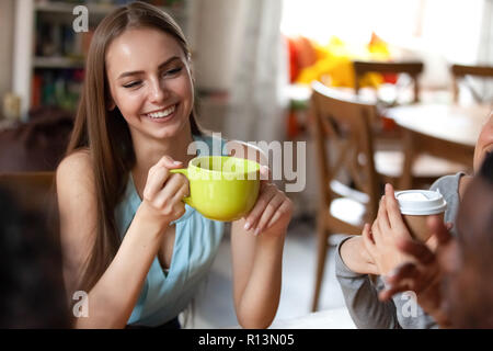 Les gens assis dans le café boissons potable se concentrer sur beautiful smiling girl est titulaire d'tasse de thé. Portrait jeune femme avec de longs cheveux passe gratuitement Banque D'Images