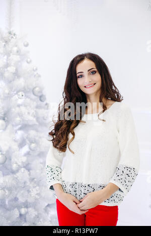 Gorgeous brunette woman posing in studio décoré contre l'arbre de Noël. Banque D'Images