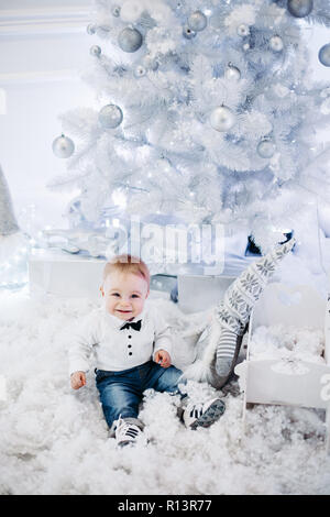 Joli bébé avec Virginie sur jersey assis dans la neige artificielle à Ch Banque D'Images