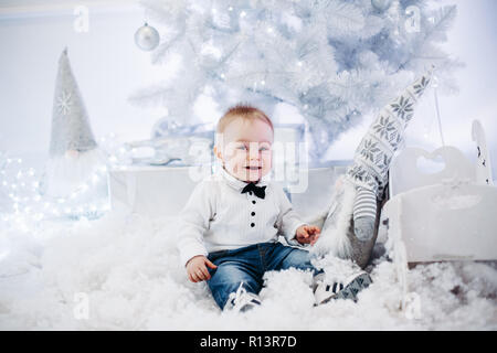 Joli bébé avec Virginie sur jersey assis dans la neige artificielle à Ch Banque D'Images