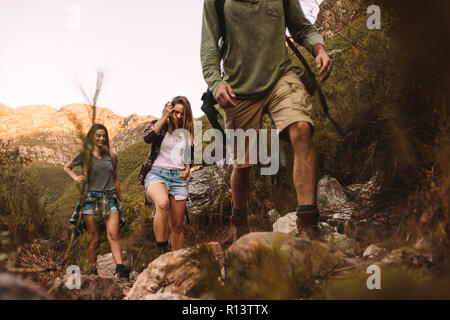 Groupe d'amis marche à travers un sentier de montagne. Jeune homme et femmes randonnées en montagne. Banque D'Images