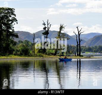 Un homme avec son chien dans un bateau à rames sur le lac Ullswater pêche,Parc National de Lake District, Cumbria, England, UK Banque D'Images