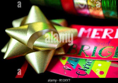 Un (1) Noël Or Satiné Ruban Bow avec papier d'emballage cadeau de Noël et le Tage. Prix pour copie. Banque D'Images