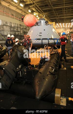 L'équipe de rétablissement de la NASA et de la Marine divers préparer la prochaine génération d'Orion capsule spatiale pour une nuit dans le test de récupération et pont de l'USS John P. Murtha, le 3 novembre 2018 dans l'océan Pacifique. La NASA et la marine américaine n'a pas effectué l'océan ouvert récupération d'un vaisseau spatial habité depuis le projet Apollo dans les années 60 et sont des procédures d'essai et le matériel qui sera utilisé pour récupérer le vaisseau Orion après il éclaboussures vers le bas dans l'océan Pacifique à la suite des futures missions d'exploration spatiale. Banque D'Images