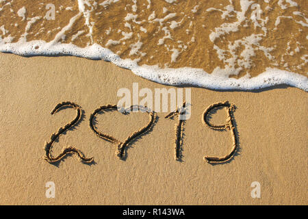 L'année 2019 et le coeur écrit sur plage de sable de mer. Vue d'en haut. Mise à plat. Banque D'Images