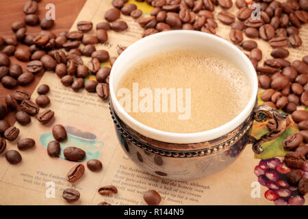 Une photo de café dans une tasse vintage, avec des grains de café, sur un vieux papier journal, tonique libre