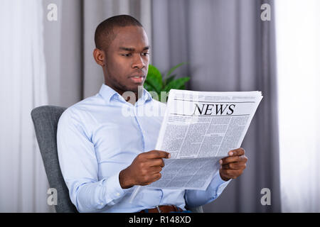 Portrait Of A Young African Man reading Newspaper Banque D'Images