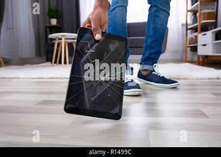 La main de l'homme prendre tablette avec écran cassé Banque D'Images