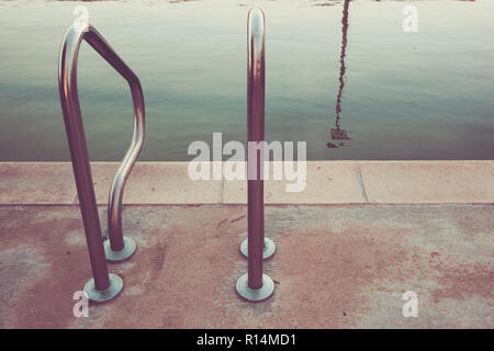 Une échelle métallique extérieure est vu d'entrer dans une piscine sale, sombre Banque D'Images