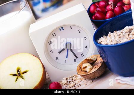 Petit-déjeuner sain - réveil, lait, le gruau, les canneberges, les noix, les pommes sur une table en bois Banque D'Images