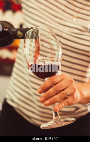 Close up woman's hands avec bouteille de vin et un verre de vin, se verse dans un verre de vin Banque D'Images