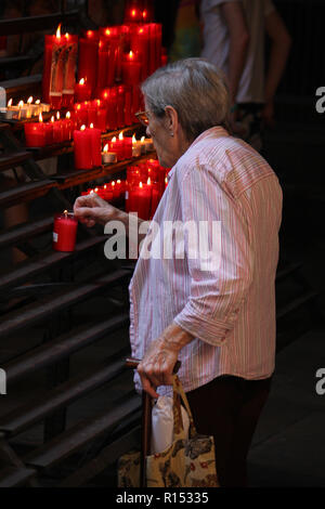 Barcelone, Espagne - 14 août 2016 : Une vieille dame allume une bougie dans une église à Barcelone, Espagne Banque D'Images