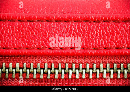 Fermeture éclair bien fermé enserrant deux couches de tissu rouge cousu cousu textile et cuir rouge sous un fort grossissement fermer détail photograp Banque D'Images