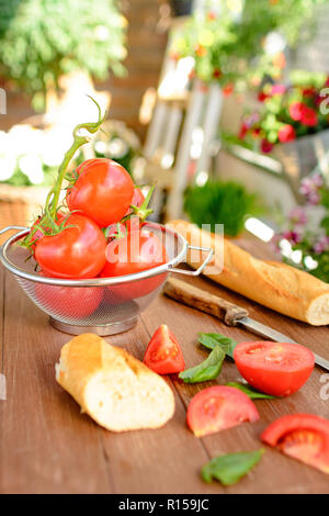 Les tomates fraîches couché dans un tamis de cuisine sur un plateau en bois Banque D'Images