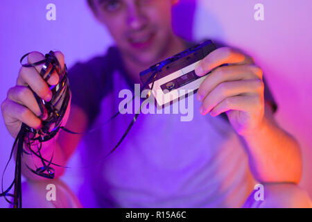 Close up of a vintage cassette audio entre les mains d'un homme en rose et violet néon, vintage,discothèque discothèque,concept Banque D'Images