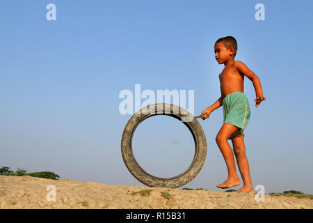 Khulna, Bangladesh - Octobre 08, 2014 : Les enfants qui jouent avec des pneus de vélo dans le village de champ à Khulna, Bangladesh. Banque D'Images