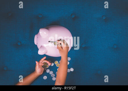 Petite fille à compter des pièces avec piggy bank Banque D'Images