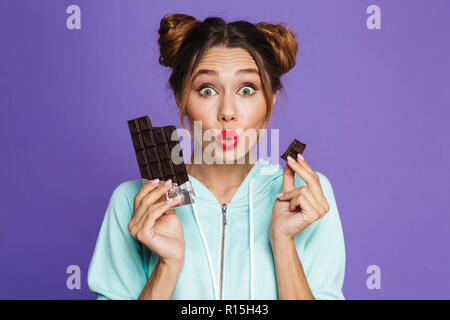 Portrait of a young girl maquillage lumineux sur fond violet, tenant une barre de chocolat Banque D'Images