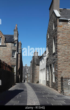 Maisons anciennes en grès Stromness, Orkney avec pierres de pavage d'une carrière locale et de galets pierres dans le centre de la rue. Banque D'Images