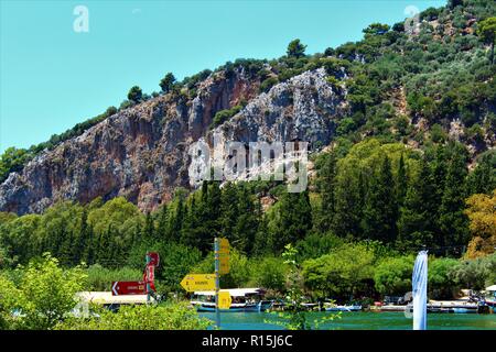 Dalyan, Turquie - 7 juillet 2018 : Les tombeaux lyciens vue au-dessus de la rivière Cayi, rempli de bateaux et les touristes. Banque D'Images