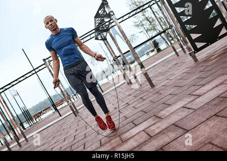 L'homme noir corde à sauter. Portrait of muscular young man exercising with jumping rope sur fond de parc national Banque D'Images