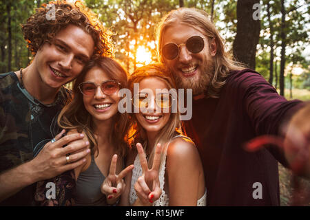 Photo de belles personnes hommes et femmes hippie souriant et prenant en selfies forest Banque D'Images