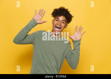 Portrait of smiling guy teint foncé coiffure afro chic d'avoir crier ou appeler sur fond jaune isolé Banque D'Images