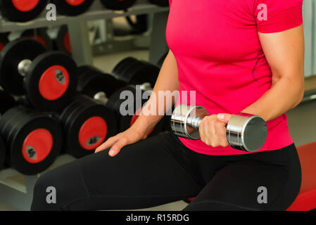 Jeune femme dans la salle de sport moderne biceps trains Banque D'Images