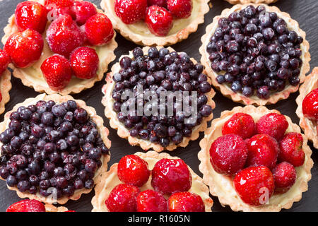 Dessert aux fruits tartelettes aux fraises et myrtilles sur table en bois. Banque D'Images