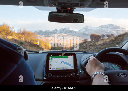 Conduite le long des rives du Loch Assynt à vers le pic de Quinag avec de la neige fraîche en automne, à partir d'une voiture avec un gps. Banque D'Images