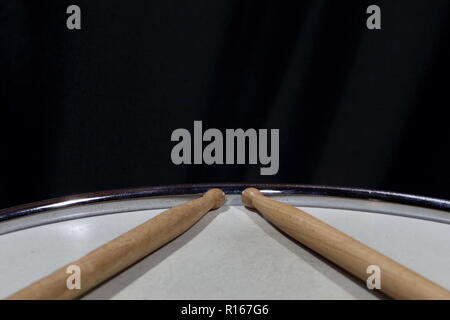 Baguettes de Tambour en bois assis sur une caisse claire sur fond sombre Banque D'Images