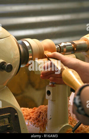 Close up of a young woman's hands le rasage un bol en bois en forme en tant qu'il tourne sur un tour Banque D'Images