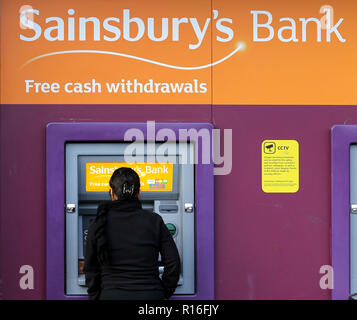 Londres, Royaume-Uni. Nov 9, 2018. Une femme est considérée en utilisant le distributeur de billets au supermarché Sainsbury's à Londres.Les supermarchés et magasins de proximité n'auront plus à payer des millions de livres dans les taux d'affaires pour les distributeurs à l'extérieur de leurs magasins, à la suite d'un arrêt de la Cour d'appel. Depuis 2010 les supermarchés et magasins de proximité ont été tenu de payer les tarifs sur les machines et la Cour d'appel a statué que sur â€300m a déjà été facturés et devront être remboursés. Les boutiques qui vont bénéficier immédiatement : Sainsburys et Tesco, qui avait pris l'affaire à Banque D'Images