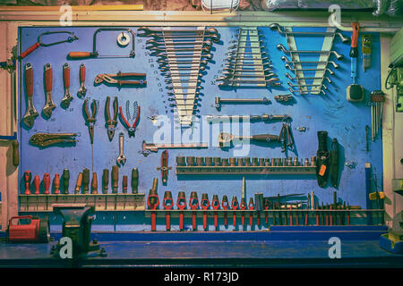 Tableau bleu dans le moteur du navire atelier avec plent différents types d'outils : clé, tournevis, ruban de mesure, vice, pinces, marteaux, etc. Banque D'Images