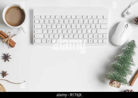 Mise à plat avec table de bureau ordinateur clavier sans fil, souris, une tasse de café , mini arbre de Noël, épices, cône de pin décoré sur le tableau blanc. Banque D'Images