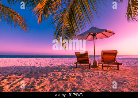 Parfait coucher de soleil sur la plage, deux chaises avec parapluie sous les palmiers. Ciel crépusculaire et tranquille sur la plage près de la mer. Maison de vacances idyllique et Banque D'Images