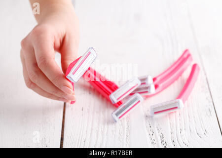 Rasoirs femme rose dans les mains sur le fond blanc. Série de rasoirs sur fond blanc. Les rasoirs jetables pour femmes rose Banque D'Images