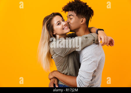 Image jeune couple aimant posant sur fond jaune isolé hugging baisers. Banque D'Images