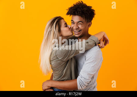 Image jeune couple aimant posant sur fond jaune isolé hugging baisers. Banque D'Images