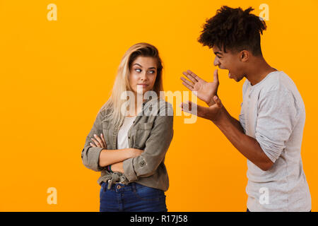 Portrait d'un couple multiethnique isolés sur fond jaune, avoir un argument Banque D'Images