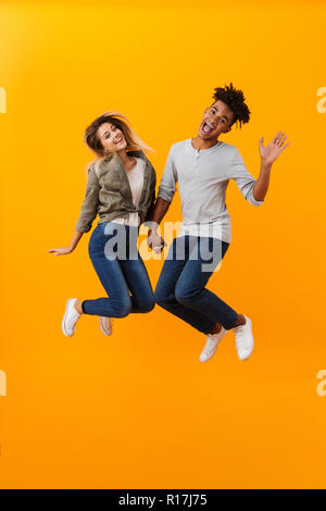 Photo de happy young couple aimant isolé sur fond jaune de saut. Banque D'Images