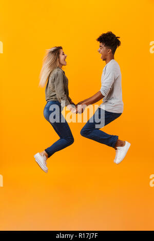 Photo de happy young couple aimant isolé sur fond jaune de saut. Banque D'Images