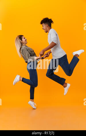 Photo de happy young couple aimant isolé sur fond jaune de saut. Banque D'Images