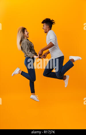 Photo de happy young couple aimant isolé sur fond jaune de saut. Banque D'Images