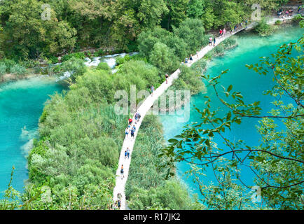 Les touristes à marcher le long d'un chemin de randonnée entre deux étangs aux eaux turquoises. Vue de dessus. Le parc national des lacs de Plitvice, Croatie Banque D'Images