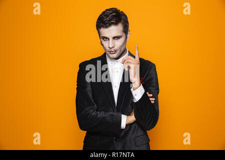 Photo de gentleman zombie terrifiant halloween costume classique sur le port et un miroir à la caméra au plus isolé sur fond jaune Banque D'Images