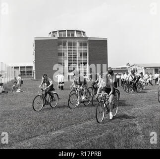 1967, historiques, à l'extérieur d'une école secondaire, dans un champ d'herbe sur les bicyclettes, les élèves prenant part à une course à vélo, England, UK. Banque D'Images